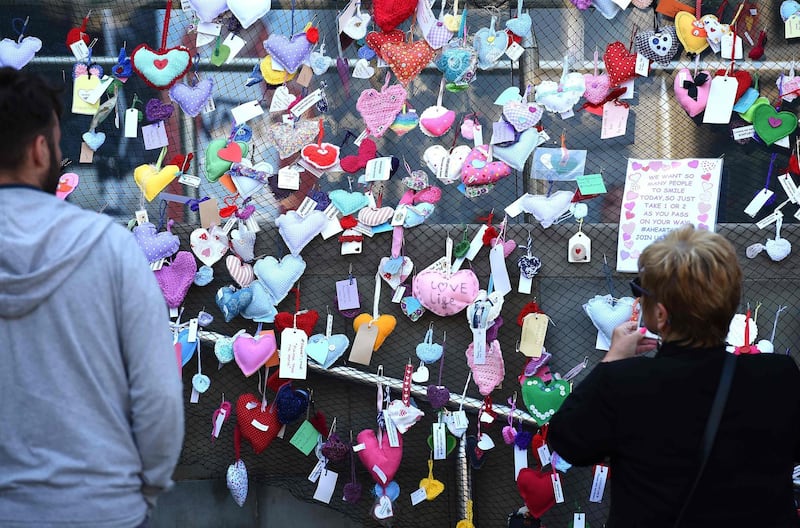 People look at a fence covered in hearts, offerings as a memorial following the Manchester Arena bombing, in central Manchester. AFP