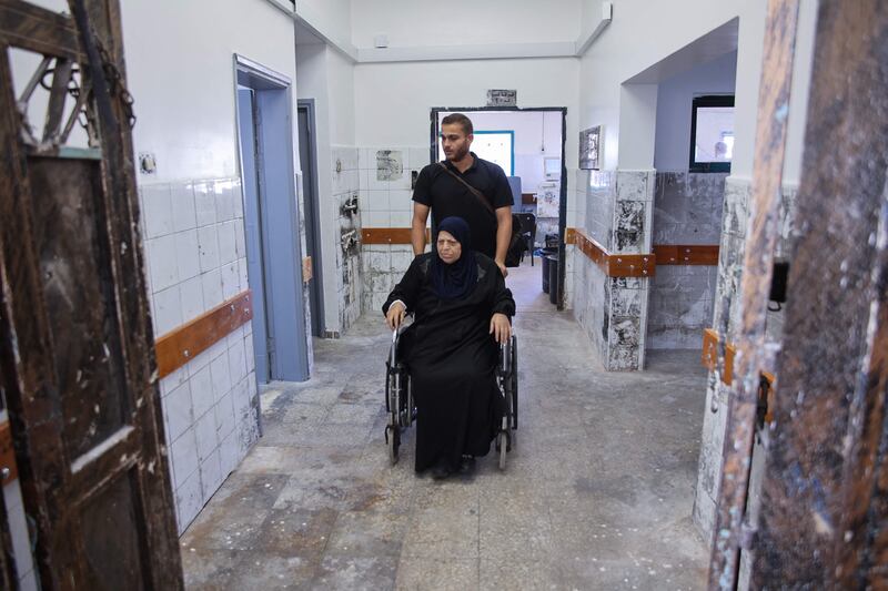 A man accompanies a patient arriving for treatment at Al-Shifa hospital's dialysis center after its rehabilitation. AFP