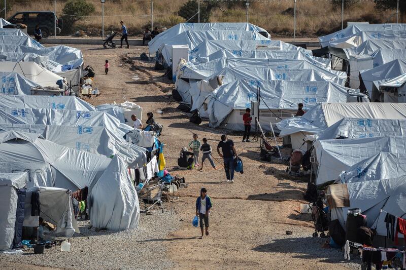 FILE - In this Wednesday, Oct. 14, 2020, file photo, migrants walk after a rainstorm at the Kara Tepe refugee camp, on the northeastern Aegean island of Lesbos, Greece. The anti-torture committee of the Council of Europe, the continent's main human rights organization, on Thursday, Nov. 19, 2020 has slammed conditions under which migrants are held in some detention centers in Greece and voiced concern over persistent allegations the country conducts illegal pushbacks of migrants. (AP Photo/Panagiotis Balaskas, File)