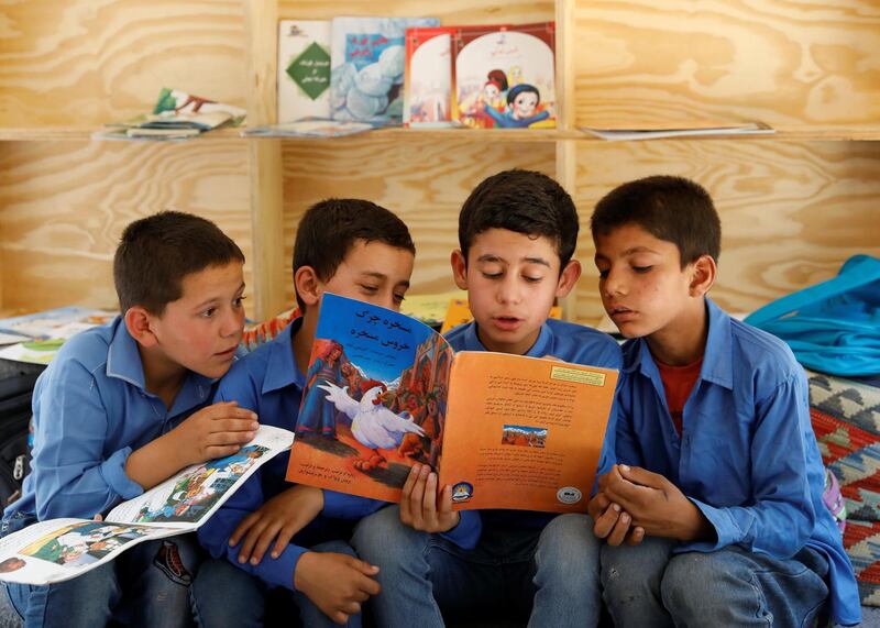 Boys read books inside a mobile library bus.