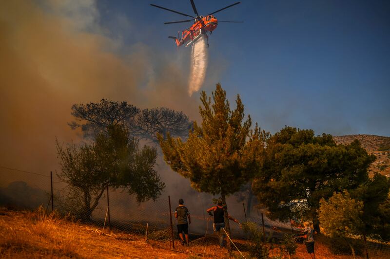 A helicopter drops water on houses to extinguish a fire in Markati.