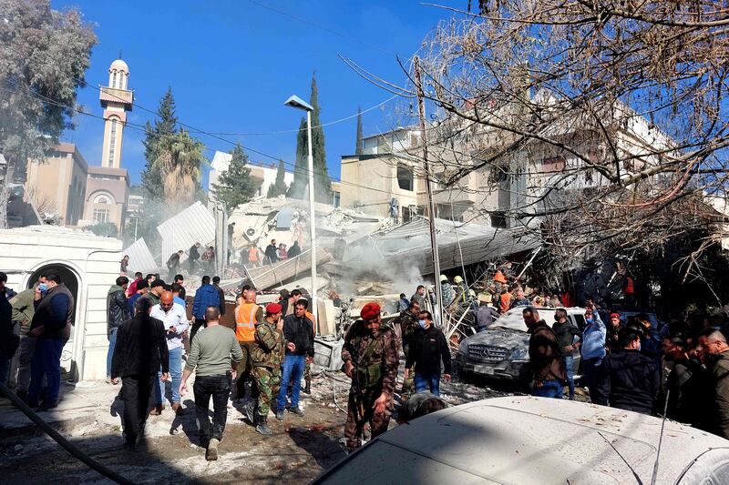Onlookers and members of the security forces gather in front of the building, which a security source said had been flattened by “precision-targeted Israeli missiles”. AFP
