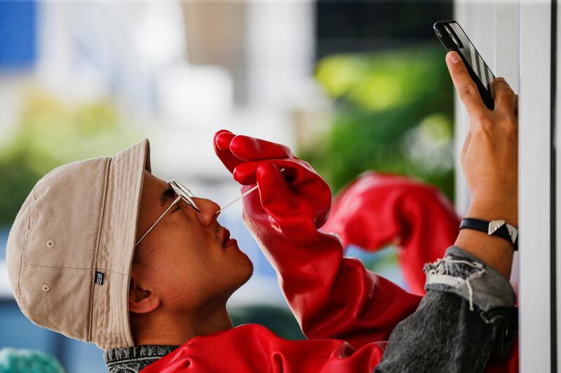 A man uses a smartphone as a medical worker collects his swab sample to be tested for the coronavirus disease (Covid-19) in Jakarta, Indonesia. Reuters