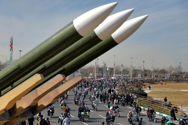 Iranians drive past missiles on their motorcycles during a rally marking the 42nd anniversary of the Islamic Revolution. AP