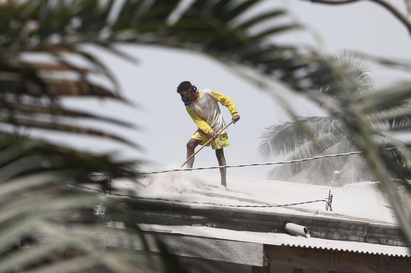 An Indonesian man cleans volcanic ash from a roof of a house after Mount Sinabung volcano spewed thick volcanic ash across the area the day before in Karo, North Sumatra. Kadri Boy Tarigan / AFP