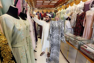 Ahmed Mohammed, pictured holding a zebra print abaya, and Masoud Abdulla at their shop in Ras Al Khaimah. Satish Kumar for The National