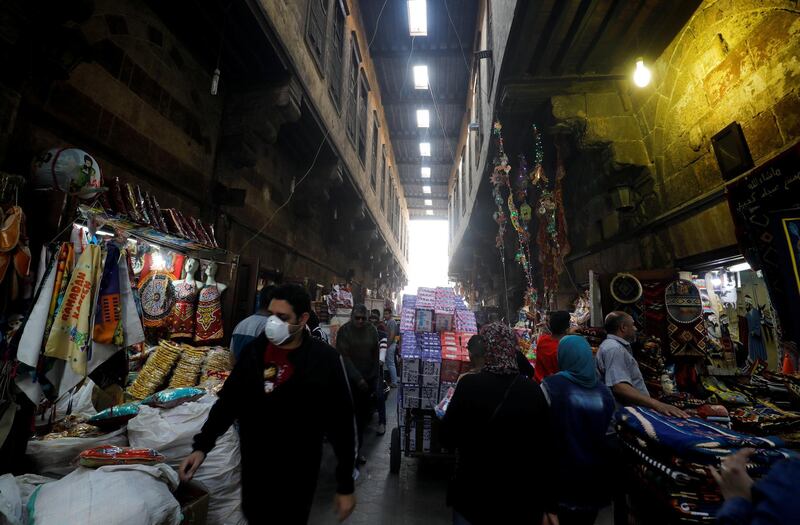 A man wearing a protective face mask walks with others near traditional Ramadan products which are displayed for sale at Al Khayamia street in old Cairo. Reuters