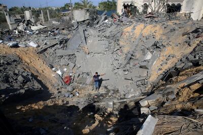 A Palestinian youth stands amid the crater of a destroyed house following overnight Israeli missile strikes, in Al-Qarara, east of Khan Younis, southern Gaza Strip, Thursday, Nov. 14, 2019. (AP Photo/Adel Hana)