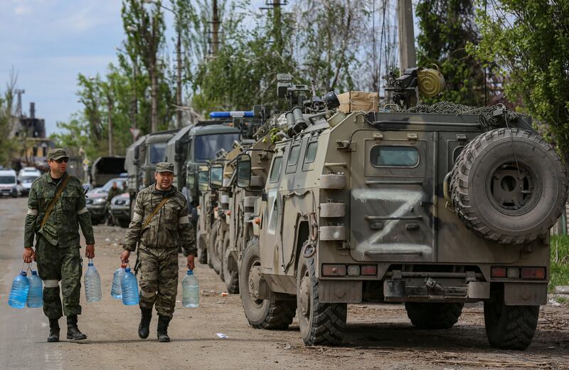 Members of the self-proclaimed Donetsk People's Republic forces carry water bottles as the evacuation of Ukrainian soldiers is carried out in Mariupo. EPA