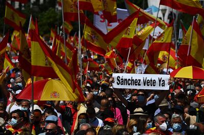TOPSHOT - A man holds a placard reading "Sanchez leave now" as others wave Spanish flags during a protest by right-wing protesters to denounce controversial Spanish government plans to offer pardons to the jailed Catalan separatists behind the failed 2017 independence bid, in Madrid on June 13, 2021. The a mass protest will up pressure on the Spanish Prime Minister  who has called for understanding over the planned gesture that has dominated political debate for weeks and reactivated the controversy over Catalan separatism.
 / AFP / GABRIEL BOUYS
