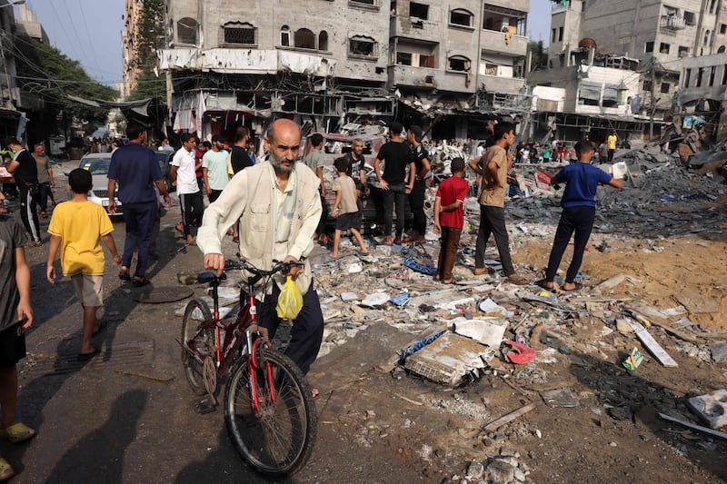 A man pushes a bicycle past the remains of buildings destroyed in Israeli strikes on Al Shatee camp in Gaza city. AFP