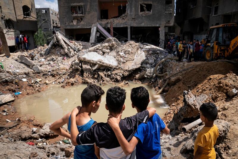 Children survey a water-filled crater where a home was destroyed by an Israeli air strike in the northern Gaza Strip. AP Photo