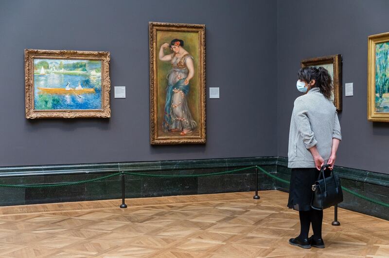 A woman wearing a face mask looks at paintings during preparations for opening at the National Gallery. EPA