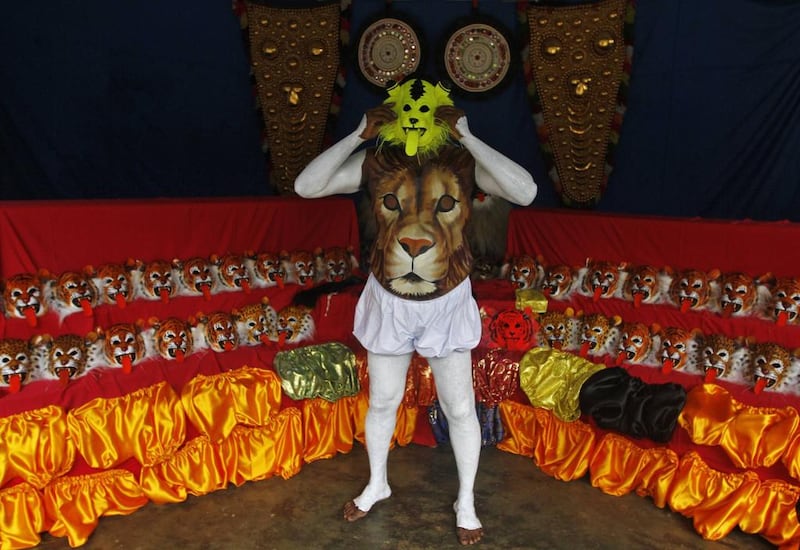 A dancer painted to look like a tiger wears a mask backstage before performing during festivities marking the end of Onam. Reuters