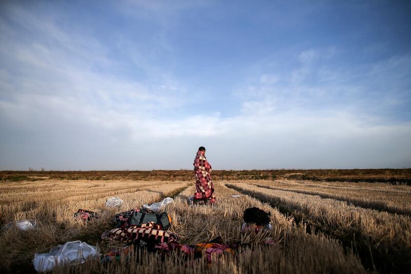 A migrant uses a blanket to warm himself in a field near Edirne, at the Turkish-Greek border on Tuesday, March 3, 2020. Migrants and refugees hoping to enter Greece from Turkey appeared to be fanning out across a broader swathe of the roughly 200-kilometer-long land border Tuesday, maintaining pressure on the frontier after Ankara declared its borders with the European Union open. (AP Photo/Emrah Gurel)