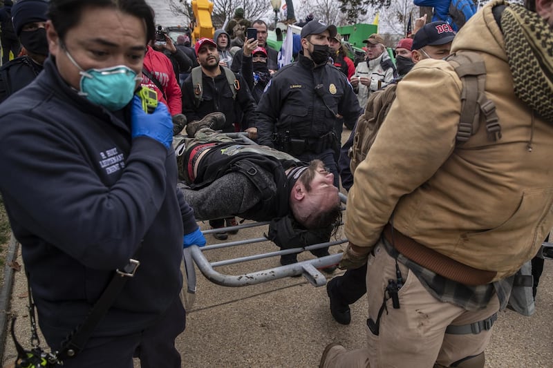 A wounded protester is carried on barricade as demonstrators breach the US Capital building grounds. Bloomberg