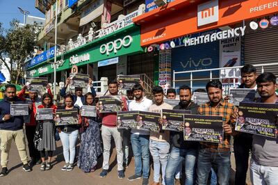 Mobile dealers and members of Ahmedabad Mobile Dealer's Association hold placards as they protest against online shopping platform Amazon outside their closed mobile shops in Ahmedabad on January 15, 2020. Amazon tycoon Jeff Bezos promised on January 15 a new billion-dollar investment in India, just two days after authorities launched an anti-trust investigation into the e-commerce giant.  / AFP / SAM PANTHAKY
