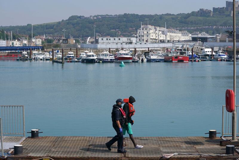 A man is escorted after disembarking from a border force boat at Dover.