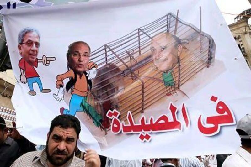 Egyptian protesters hold a banner with manipulated photos showing presidential hopefuls (L-R) Amr Moussa, Ahmed Shafik, and Omar Suleiman during a protest in Cairo this month.