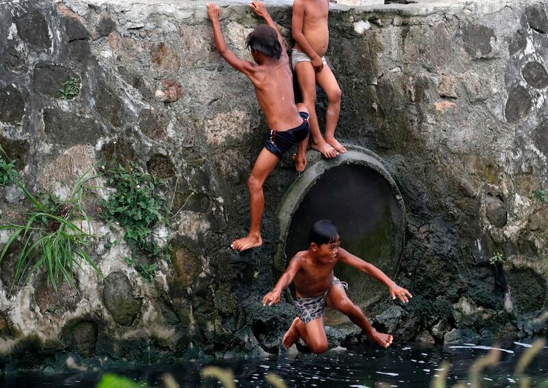 Children play next to a sewage pipe along the Laguna de Bay in Taguig City, Metro Manila, Philippines. EPA