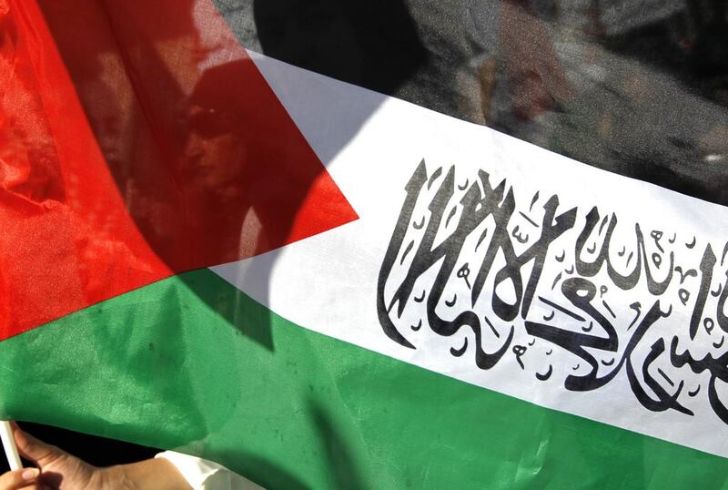 Palestinian protesters stand behind a national flag with an islamic writing during a demonstration to support the resistance in Gaza (Photo: AFP PHOTO / ABBAS  MOMANI)


