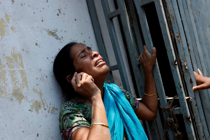 epa03674805 A woman cries as she talks on a telephone following the eight-storey Rana Plaza building collapse at Savar in Dhaka, Bangladesh, 24 April 2013. At least 20 people died including garment workers and many more were critically injured, reports said.  EPA/ABIR ABDULLAH *** Local Caption ***  03674805.jpg