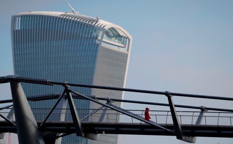 A lone pedestrian walks across the Millennium Bridge with the 20 Fenchurch Street skyscraper  in the background in London. AFP