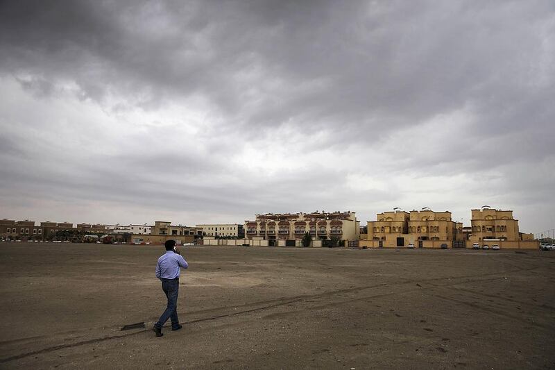 A man walks across a saturated sand lot under a cloudy, moody sky in Mohammed bin Zayed City. Gloomy, rainy conditions yesterday and on Tuesday evening kept police response teams and municipality workers busy. Silvia Razgova / The National