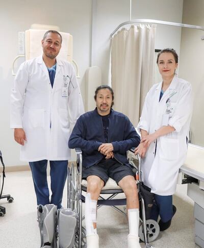 Waiwah Yip, in a wheelchair after his mountain fall, pictured with doctors Omar Sabri, left, and Otilia Fustos at Saudi German Hospital, Dubai. Photo: Waiwah Yip