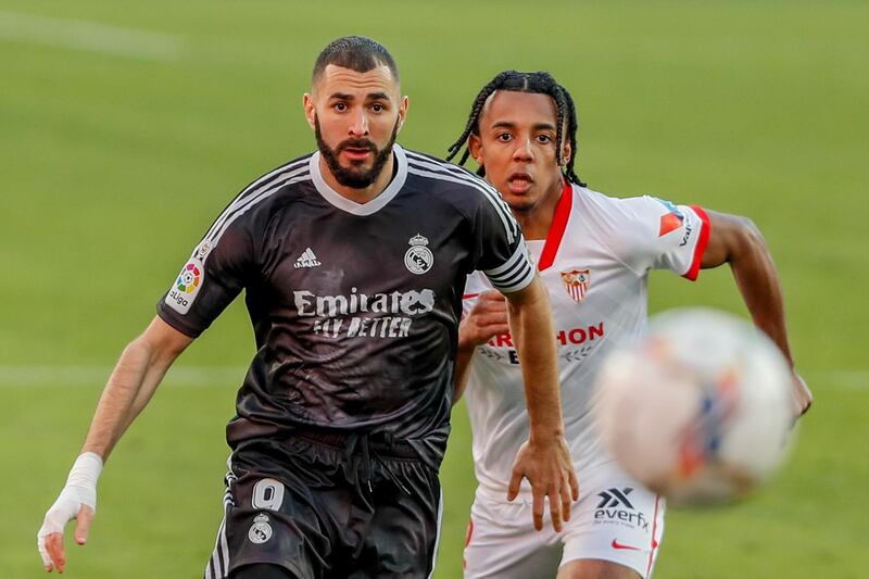 Real Madrid's Karim Benzema, left, challenges for the ball with Sevilla's Jules Kounde. AP