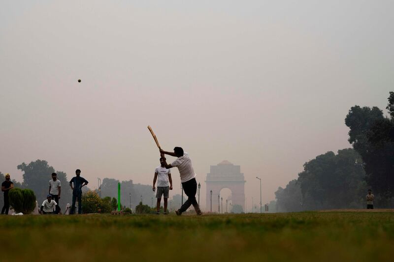 Youths play cricket in a park near India Gate in New Delhi on Tuesday, October 29. AFP