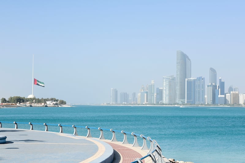 The UAE flag flies at half-staff, with the Abu Dhabi skyline in the background, after the death of the President, Sheikh Khalifa. Khushnum Bhandari / The National
