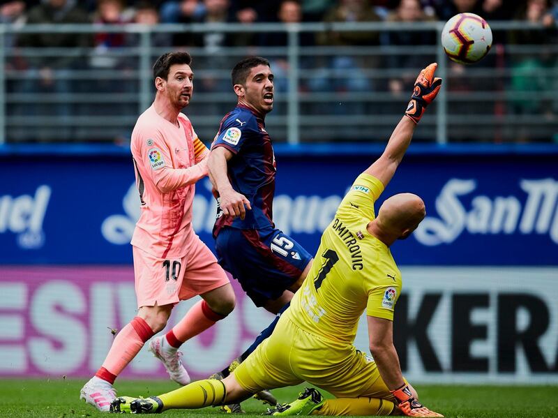 Messi shoots to score in front Eibar's goalkeeper Marko Dmitrovic and Eibar's Cote. AP Photo