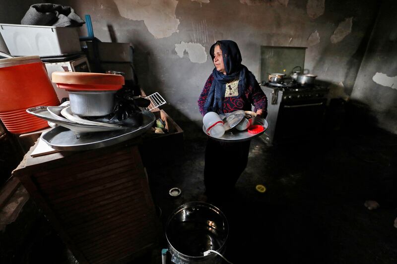 A woman works in the kitchen of her damaged house.  