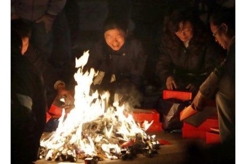 Relatives of people who died in the Shanghai apartment fire burn paper money for the deceased to use in the afterlife.