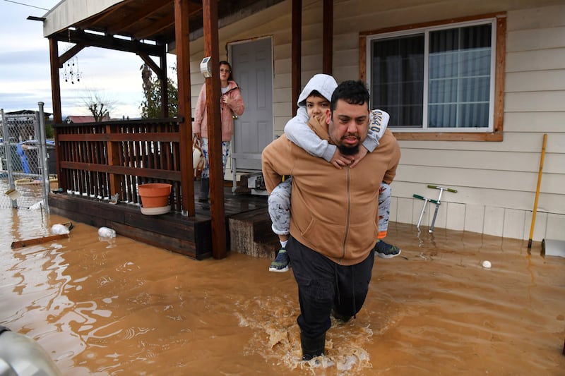 A man carries a child from their home in Brentwood. AP