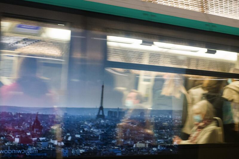 Morning rush hour commuters wear protective face masks while passing a poster showing the Eiffel Tower in Paris, France. Bloomberg