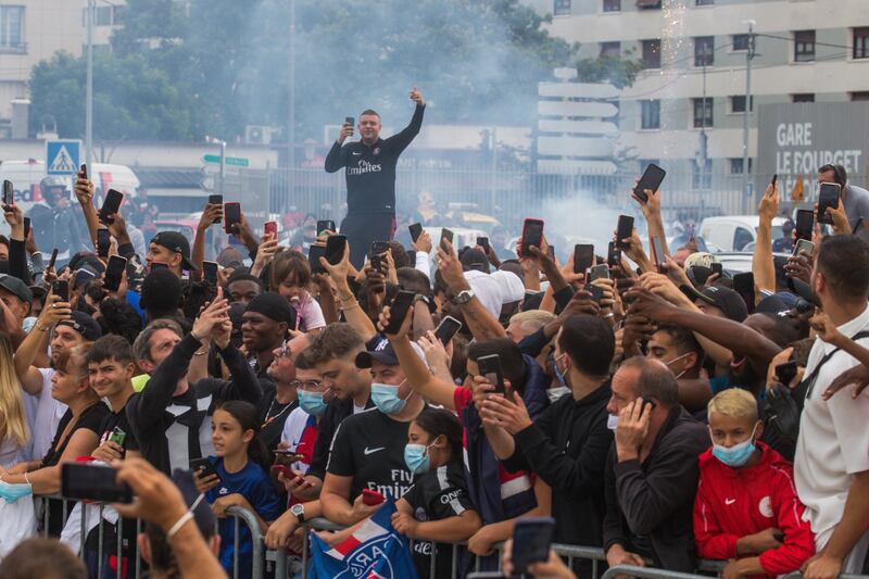 PSG fans gather outside Le Bourget Airport in Paris waiting for the arrival of Lionel Messi.