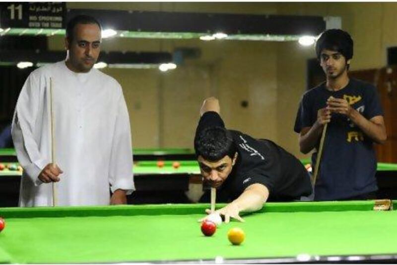 Mohammed Shehab practises at Dubai Snooker Club while his World Cup teammate Mohammed Al Joker, left, looks on along with up and coming star Khalid Kamali.
