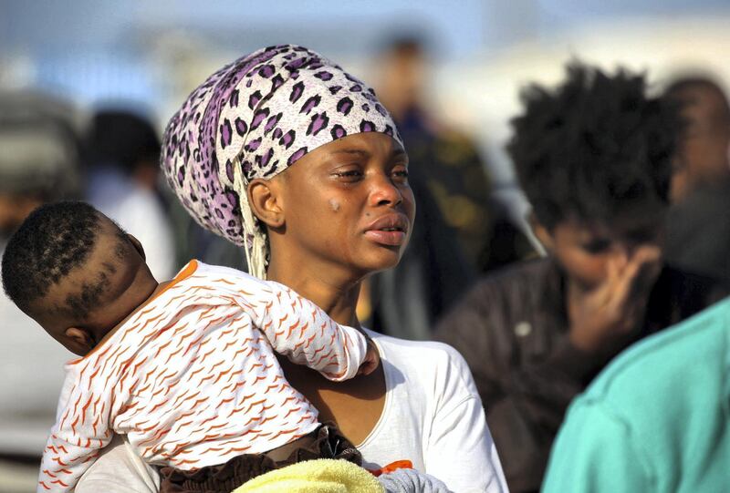 A woman cries as illegal migrants of different African nationalities arrive at a naval base in the capital Tripoli on May 6, 2018, after they were rescued from inflatable boat off the coast of Al-Zawiyah. (Photo by MAHMUD TURKIA / AFP)