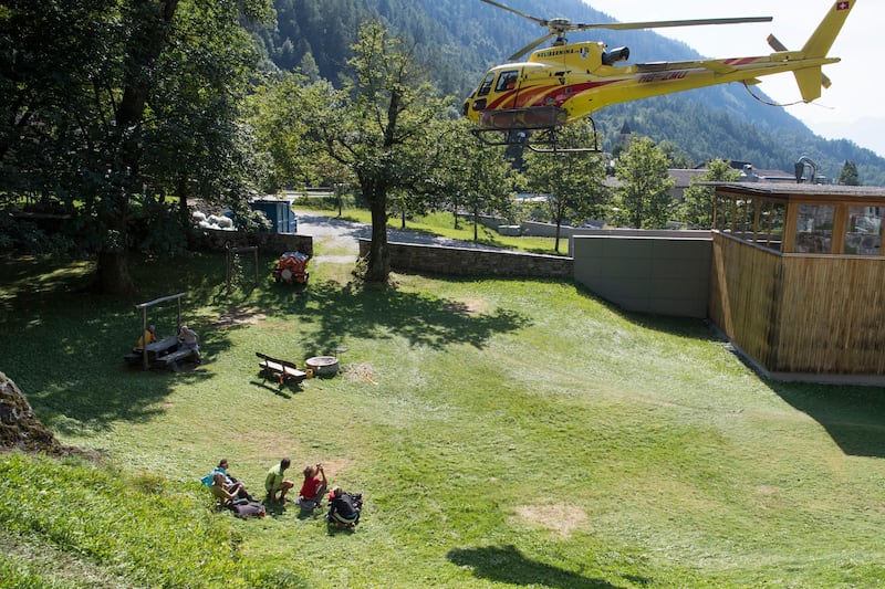 A group of hikers duck after being rescued from a cut-off mountain hut in Bondi, Graubuenden, South Switzerland, Thursday, Aug. 24, 2017. Rescue workers are using a helicopter and dogs to search for at least eight people still unaccounted for in the Swiss Alpine valley, a day after a mudslide and rockslide hit the small village near the Italian border. (Gian Ehrenzeller/Keystone via AP)