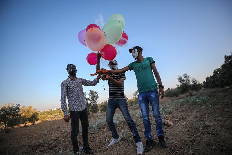Demonstrators hold balloons loaded with flammable material near the Gaza-Israel border.