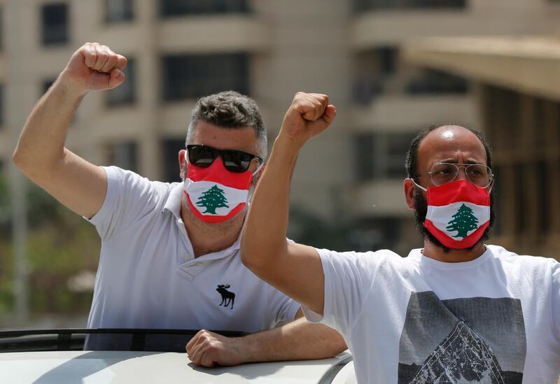 Anti-government protesters shout slogans, while wearing masks with the colors of the Lebanese flag to help curb the spread of the coronavirus, during a driving convoy protest through the streets to express rejection of the political leadership.  AP