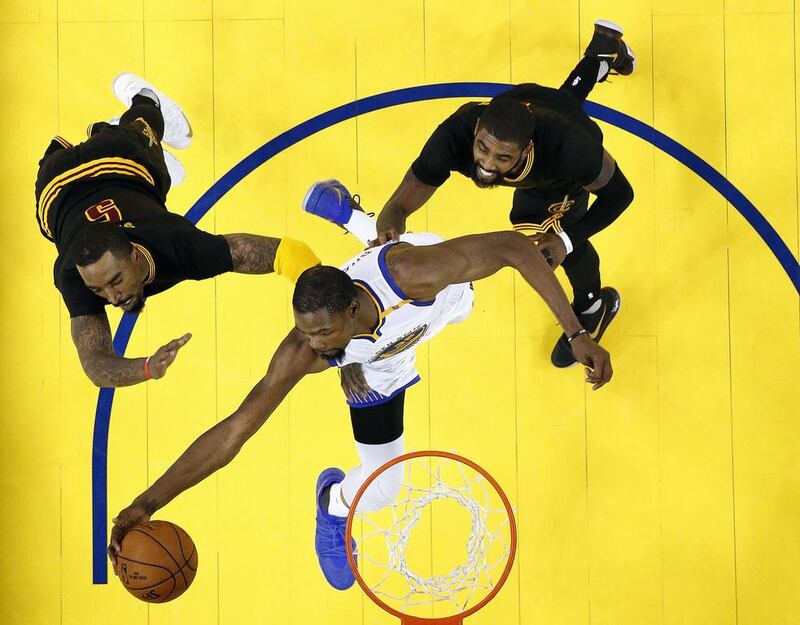 Golden State Warriors forward Kevin Durant, bottom, reaches for the ball between Cleveland Cavaliers guard JR Smith, left, and guard Kyrie Irving during Game 5 of basketball’s NBA Finals in Oakland, California. The Warriors won 129-120 to win the NBA championship. Monica Davey / Pool Photo via AP