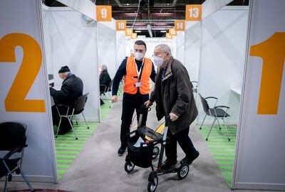 Manfred Soeder is helped by a volunteer following his registration at the temporary vaccination centre of the Erika-Hess ice stadium to fight the coronavirus disease (COVID-19) pandemic in Berlin, Germany, January 14, 2021. Kay Nietfeld/Pool via REUTERS