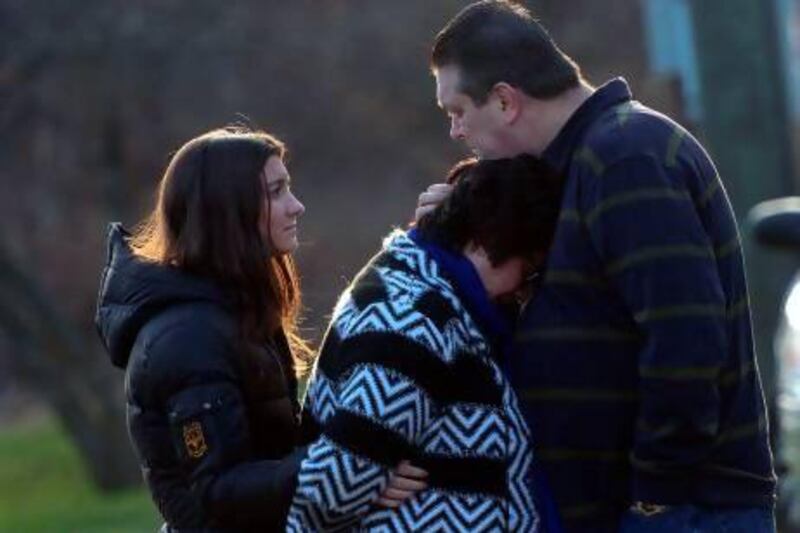 TOPSHOTS A couple and their daughter grieve after paying tribute to the victims of an elementary school shooting in Newtown, Connecticut, on December 15, 2012. A young gunman slaughtered 20 small children and six teachers on December 14 after walking into a school in an idyllic Connecticut town wielding at least two sophisticated firearms. AFP PHOTO/Emmanuel DUNAND
 *** Local Caption *** 111675-01-08.jpg