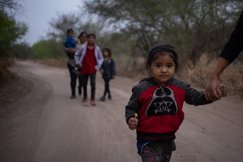 Taznari, a three-year-old asylum-seeking migrant girl from Honduras, holds her mother’s hand as they walk down a dirt road after crossing the Rio Grande river into the United States from Mexico on a raft in Penitas, Texas, U.S., March 16, 2021. REUTERS/Adrees Latif