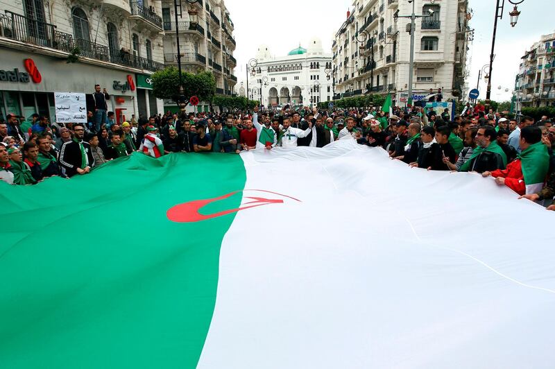 Algerians wave a giant national flag during an anti-government demonstration in the capital Algiers. AFP