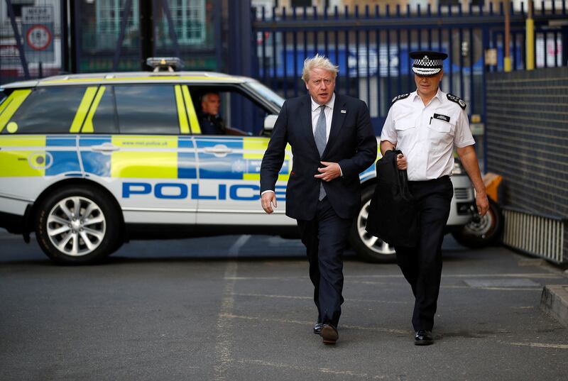 Mr Johnson with Stephen House, acting commissioner of the Metropolitan Police service, during a visit to a police station in London. Getty Images