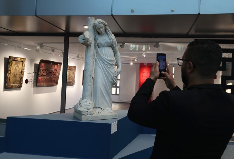 A man takes a photo of the white marble statue representing a woman leaning on a large cross located to his right, early 20th century at heritage exhibition entitled 'Our heritage is an inestimable wealth' in Tunis, Tunisia, 18 February 2022.  374 exhibited artifacts dating from ancient eras and civilizations, which Tunisia has managed to recover and seize these last years.  These artifacts were selected from more than 40,000 pieces that were recovered and seized as part of the efforts of the National Heritage Institute in Tunisia between 2012 and 2019.   EPA / MOHAMED MESSARA